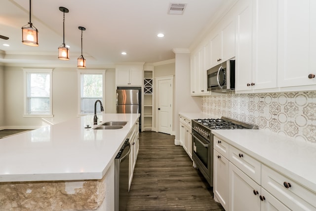 kitchen with dark wood-type flooring, a center island with sink, sink, appliances with stainless steel finishes, and white cabinetry