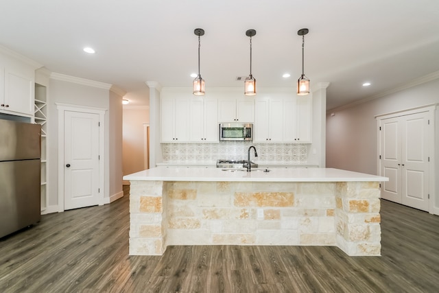 kitchen with appliances with stainless steel finishes, white cabinetry, dark wood-type flooring, and an island with sink