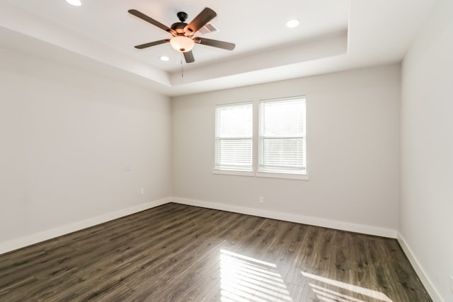 empty room featuring a tray ceiling, ceiling fan, and dark hardwood / wood-style flooring