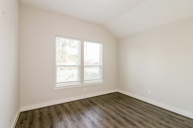 spare room with vaulted ceiling and dark wood-type flooring