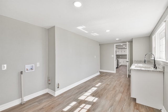 kitchen featuring light stone countertops, light wood-type flooring, stainless steel range, and sink