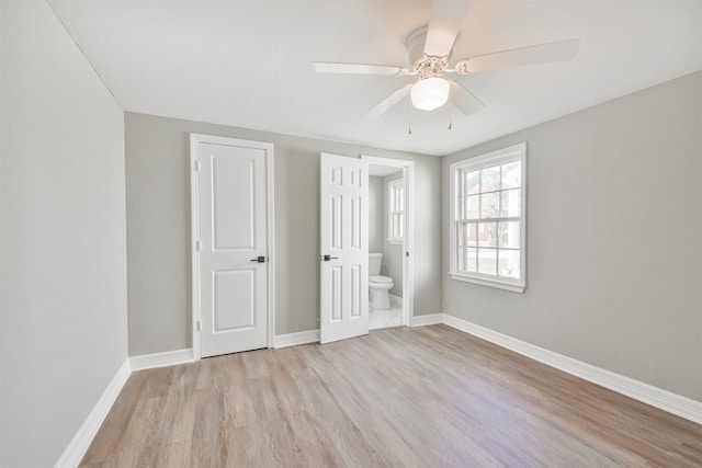 unfurnished bedroom featuring ceiling fan, ensuite bathroom, and light hardwood / wood-style flooring