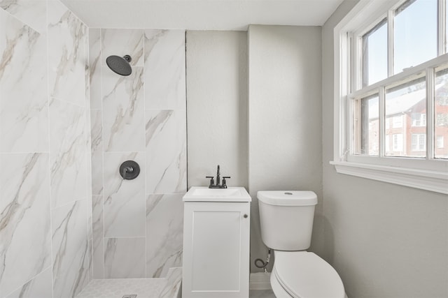 bathroom with a tile shower, sink, and toilet