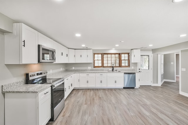 kitchen featuring stainless steel appliances, white cabinetry, plenty of natural light, and light hardwood / wood-style flooring