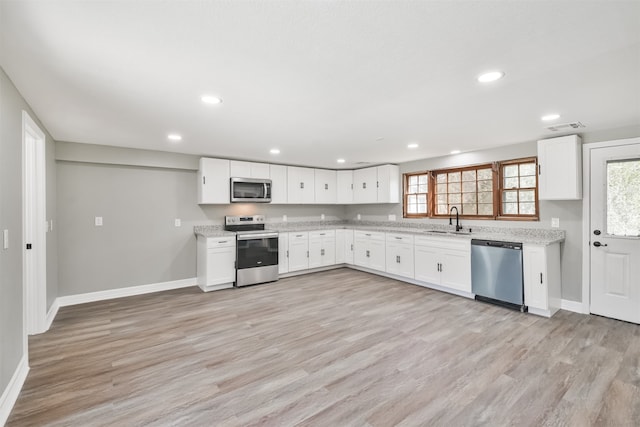 kitchen with white cabinets, stainless steel appliances, light hardwood / wood-style floors, and sink