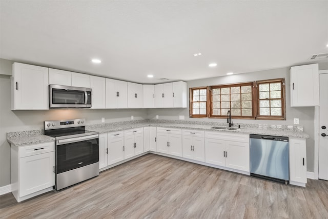 kitchen featuring white cabinetry, sink, light hardwood / wood-style floors, and appliances with stainless steel finishes