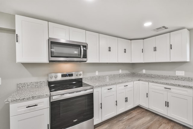 kitchen featuring white cabinets, light hardwood / wood-style floors, light stone counters, and stainless steel appliances