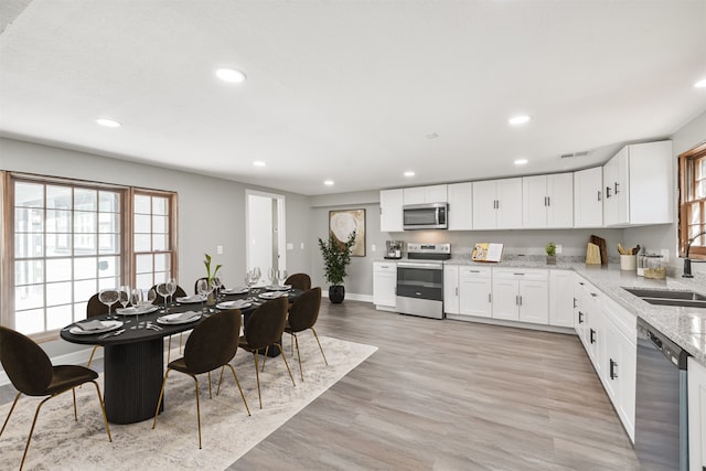 kitchen with white cabinetry, stainless steel appliances, and light hardwood / wood-style floors