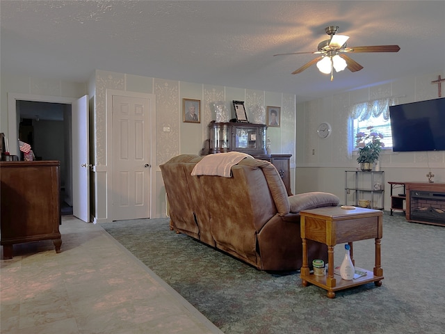 carpeted living room featuring ceiling fan and a textured ceiling