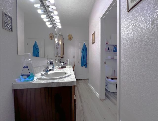 bathroom featuring vanity, wood-type flooring, a textured ceiling, and toilet