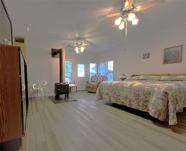 bedroom featuring light hardwood / wood-style floors, a wood stove, and ceiling fan