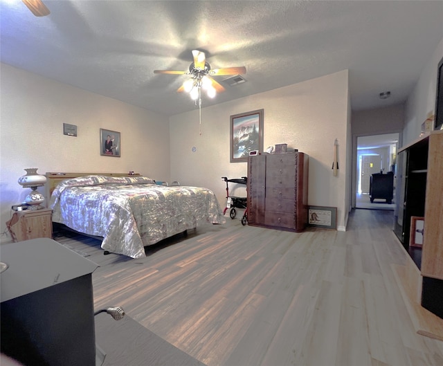 bedroom with ceiling fan, hardwood / wood-style floors, and a textured ceiling