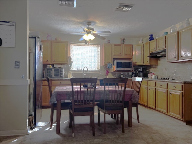 kitchen with a textured ceiling, light stone counters, ceiling fan, and backsplash