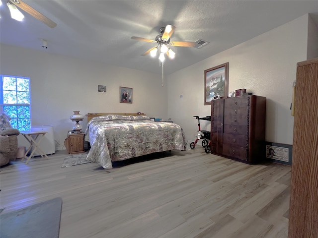 bedroom featuring ceiling fan, light hardwood / wood-style flooring, and a textured ceiling