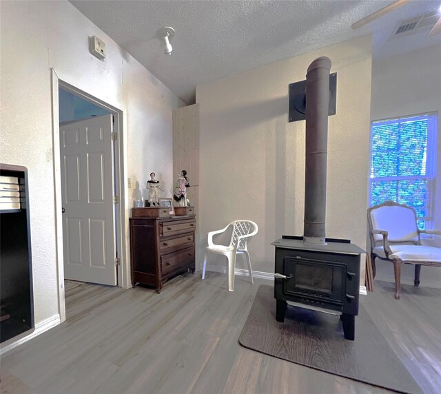 living room with a textured ceiling, hardwood / wood-style flooring, and a wood stove