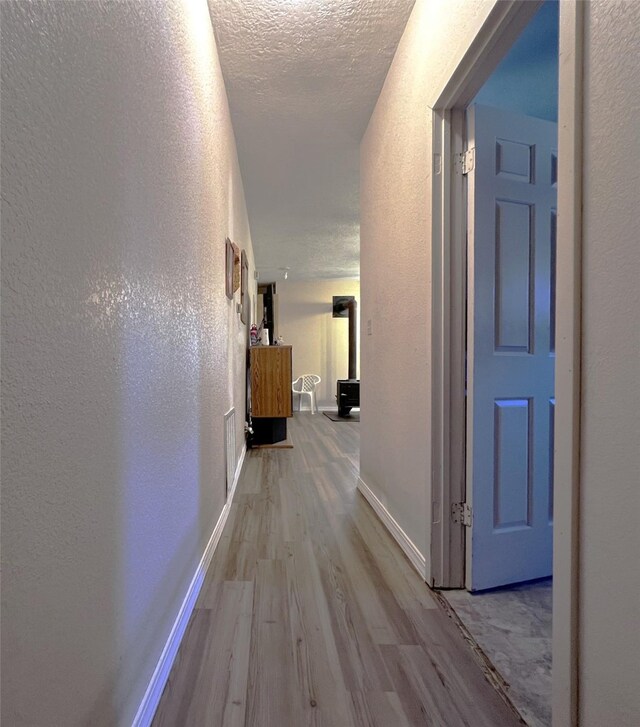 hallway with a textured ceiling and light wood-type flooring