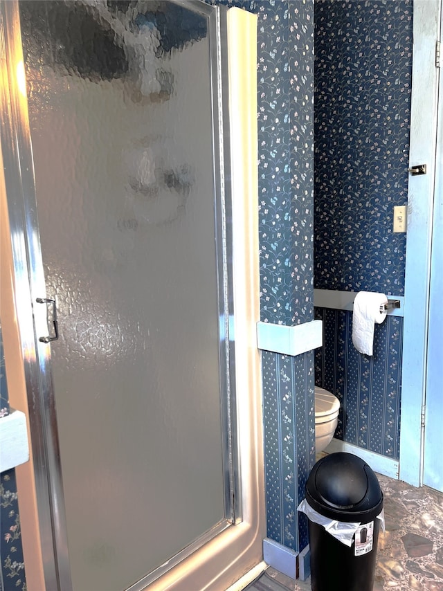 bathroom featuring toilet and a shower with door