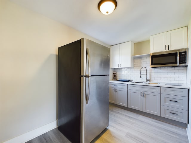 kitchen with gray cabinetry, sink, light hardwood / wood-style flooring, white cabinetry, and stainless steel appliances