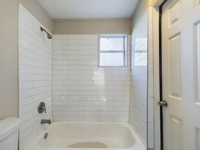 bathroom with toilet and tiled shower / bath