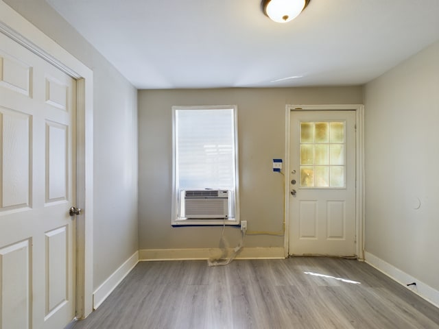 foyer entrance featuring cooling unit, light wood-type flooring, and a wealth of natural light