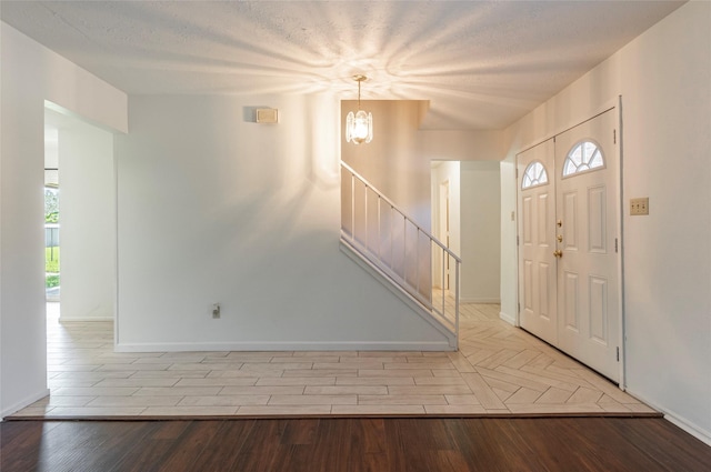 foyer with light hardwood / wood-style flooring, a chandelier, and a textured ceiling