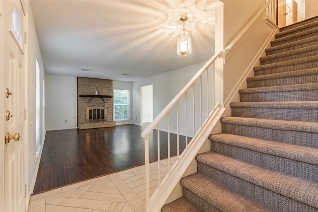 stairway with hardwood / wood-style floors and a brick fireplace