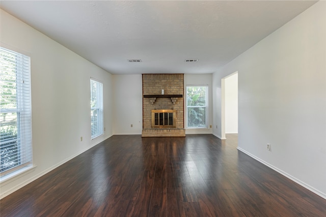 unfurnished living room with dark hardwood / wood-style flooring and a brick fireplace