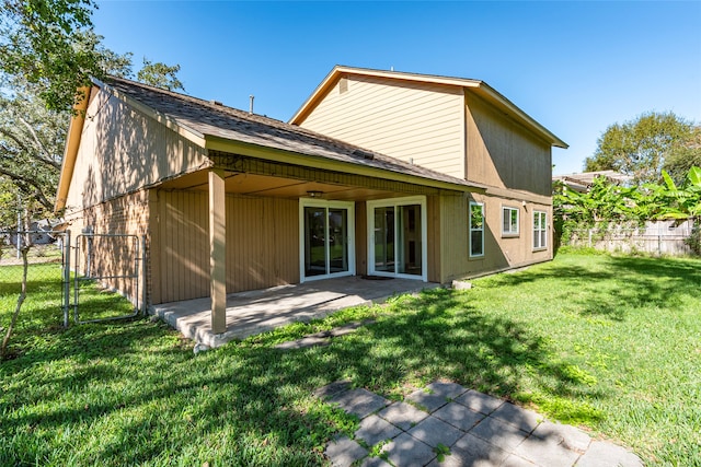 rear view of house featuring a lawn and a patio