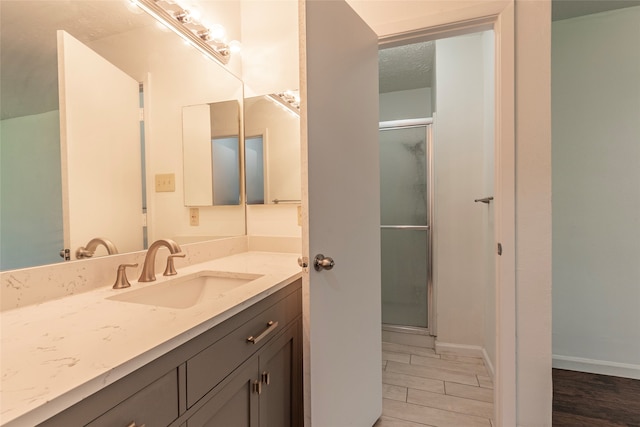 bathroom with hardwood / wood-style floors, vanity, and a shower with door