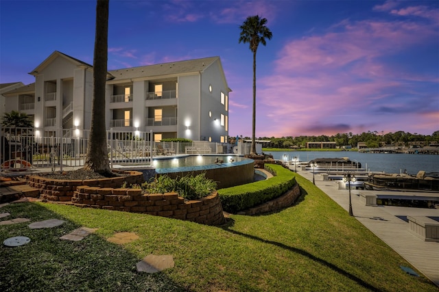 surrounding community with a water view, a yard, and a dock