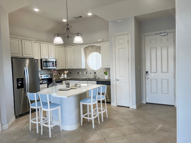 kitchen featuring a center island, tasteful backsplash, a chandelier, decorative light fixtures, and appliances with stainless steel finishes