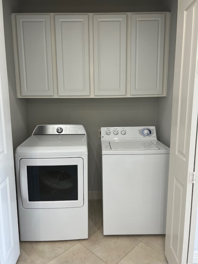 laundry area featuring cabinets, separate washer and dryer, and light tile patterned flooring