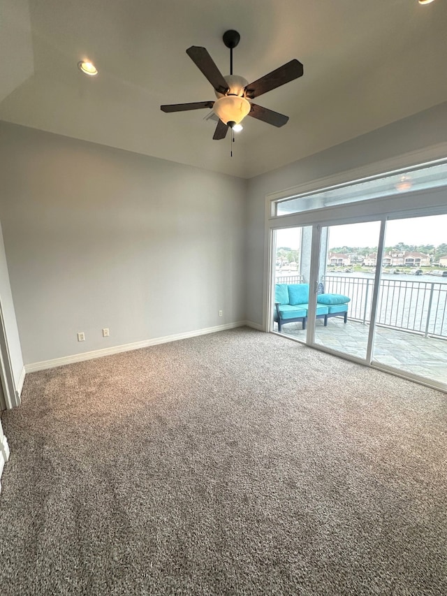 carpeted spare room featuring a water view and ceiling fan