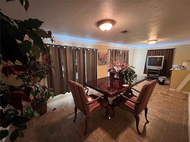 dining room with a textured ceiling and crown molding