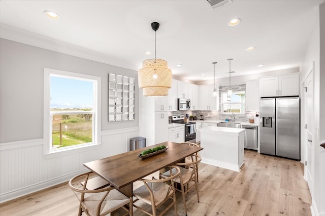 dining area featuring ornamental molding, sink, and light hardwood / wood-style flooring