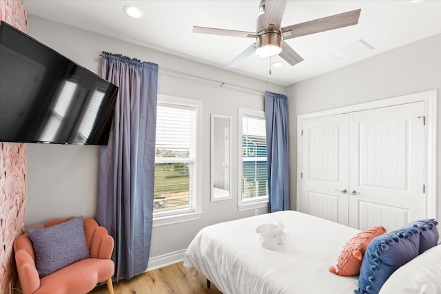 bedroom with a closet, multiple windows, light hardwood / wood-style floors, and ceiling fan