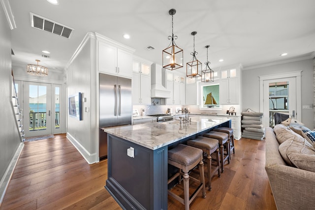 kitchen with premium range hood, a center island with sink, stainless steel appliances, and dark hardwood / wood-style floors