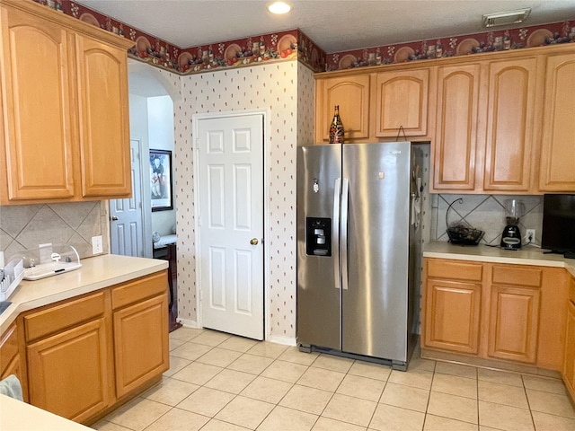 kitchen featuring stainless steel fridge, tasteful backsplash, and light tile patterned floors