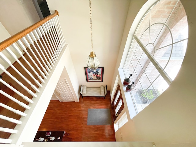 stairway featuring a chandelier, a high ceiling, and hardwood / wood-style floors