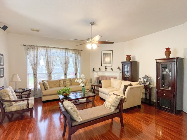 living room featuring a brick fireplace, ceiling fan, and dark wood-type flooring