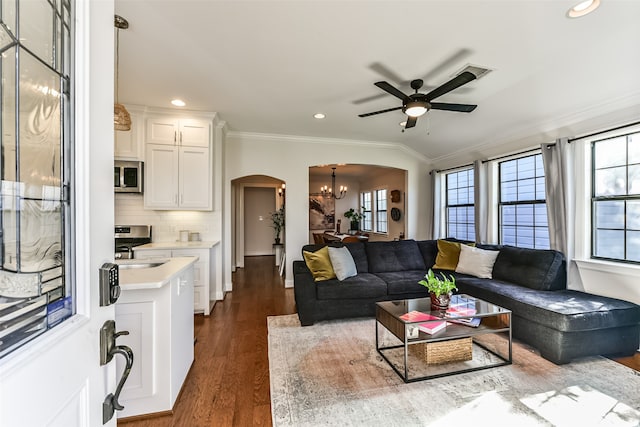 living room with crown molding, dark hardwood / wood-style flooring, ceiling fan with notable chandelier, and lofted ceiling