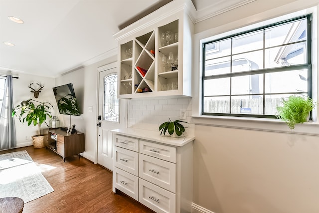 bar with plenty of natural light, dark hardwood / wood-style floors, white cabinetry, and backsplash