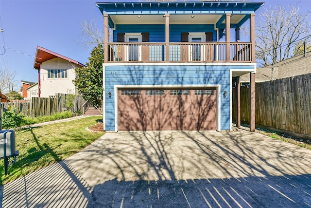 view of front of house featuring a garage, a balcony, and a front lawn