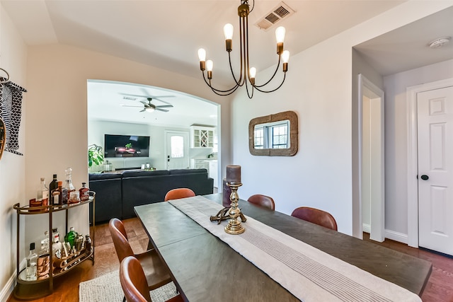 dining area with vaulted ceiling, ceiling fan with notable chandelier, and dark hardwood / wood-style floors