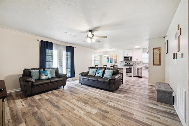 living room featuring ceiling fan, a textured ceiling, and light hardwood / wood-style flooring