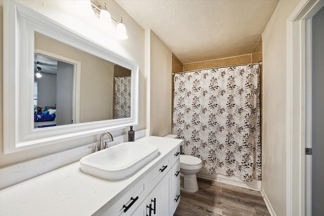 bathroom featuring vanity, a textured ceiling, ceiling fan, wood-type flooring, and toilet