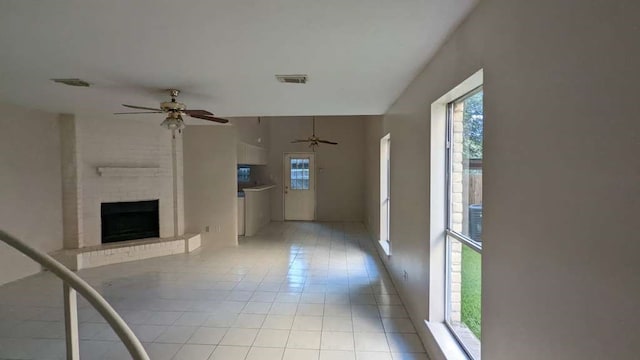 unfurnished living room featuring light tile patterned flooring and a brick fireplace