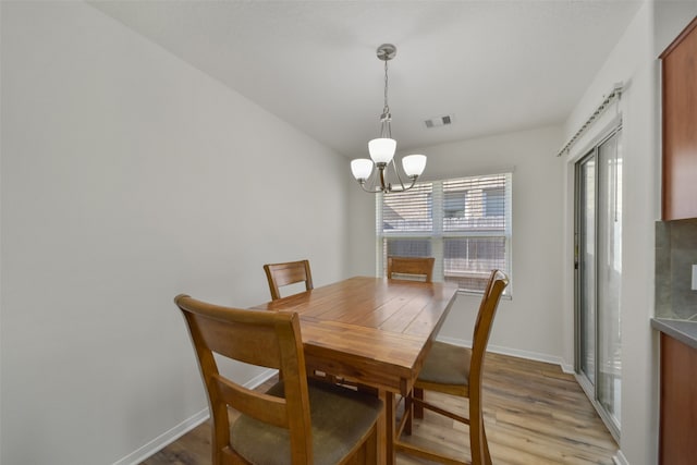 dining room featuring light wood-type flooring and a chandelier