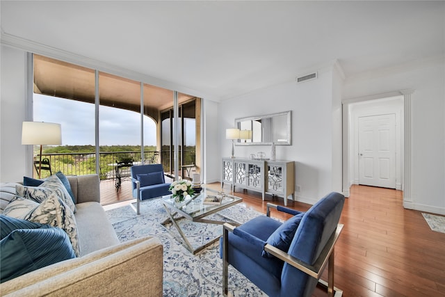 living room with wood-type flooring, expansive windows, and ornamental molding