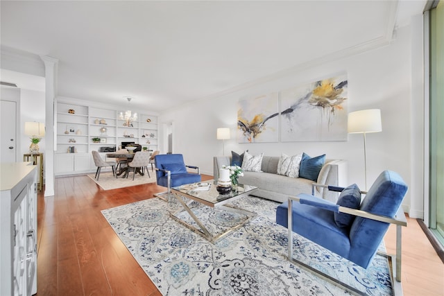 living room featuring a notable chandelier, crown molding, and light hardwood / wood-style flooring